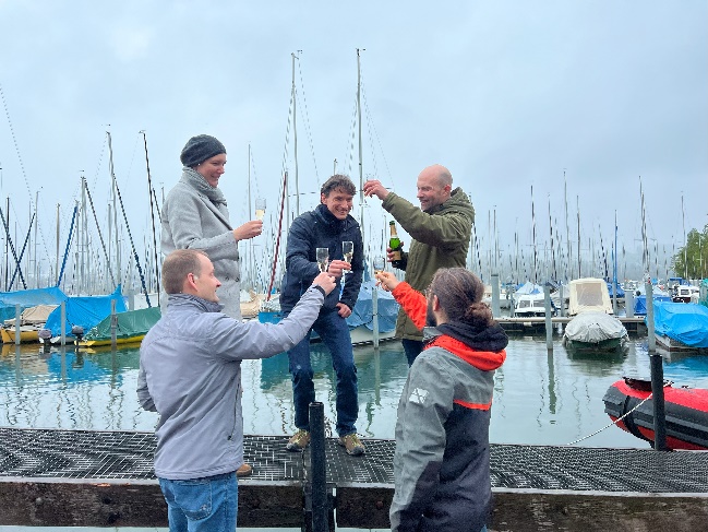 A group of people standing on a dock holding glasses of champagne

Description automatically generated